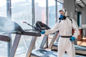 Man in hazmat suit COVID cleaning gym equipment