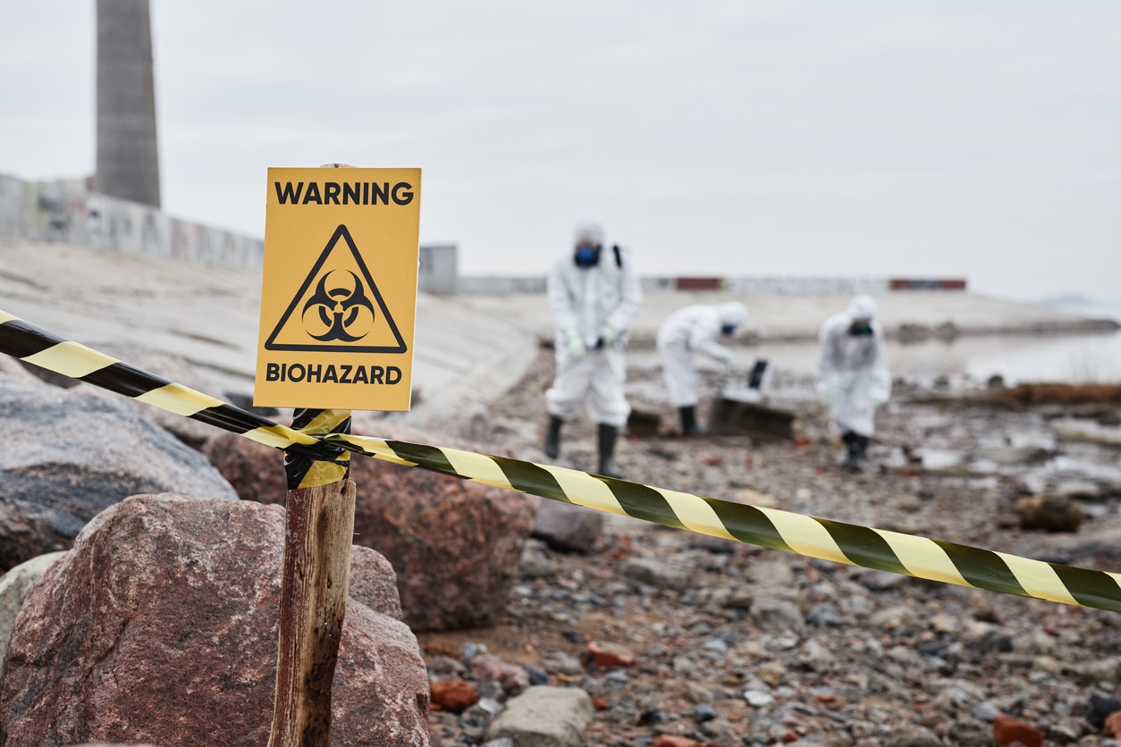 Biohazard Sign with men in biohazard suits cleaning up after a death