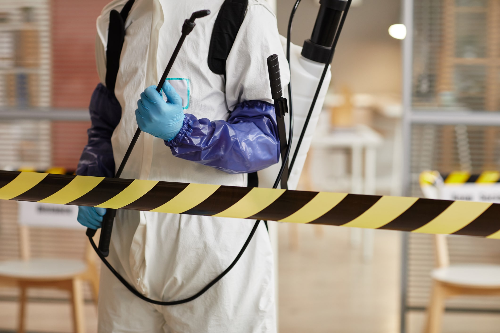 Biohazard Cleanup Technician wearing full Hazmat Gear while Sanitizing Office